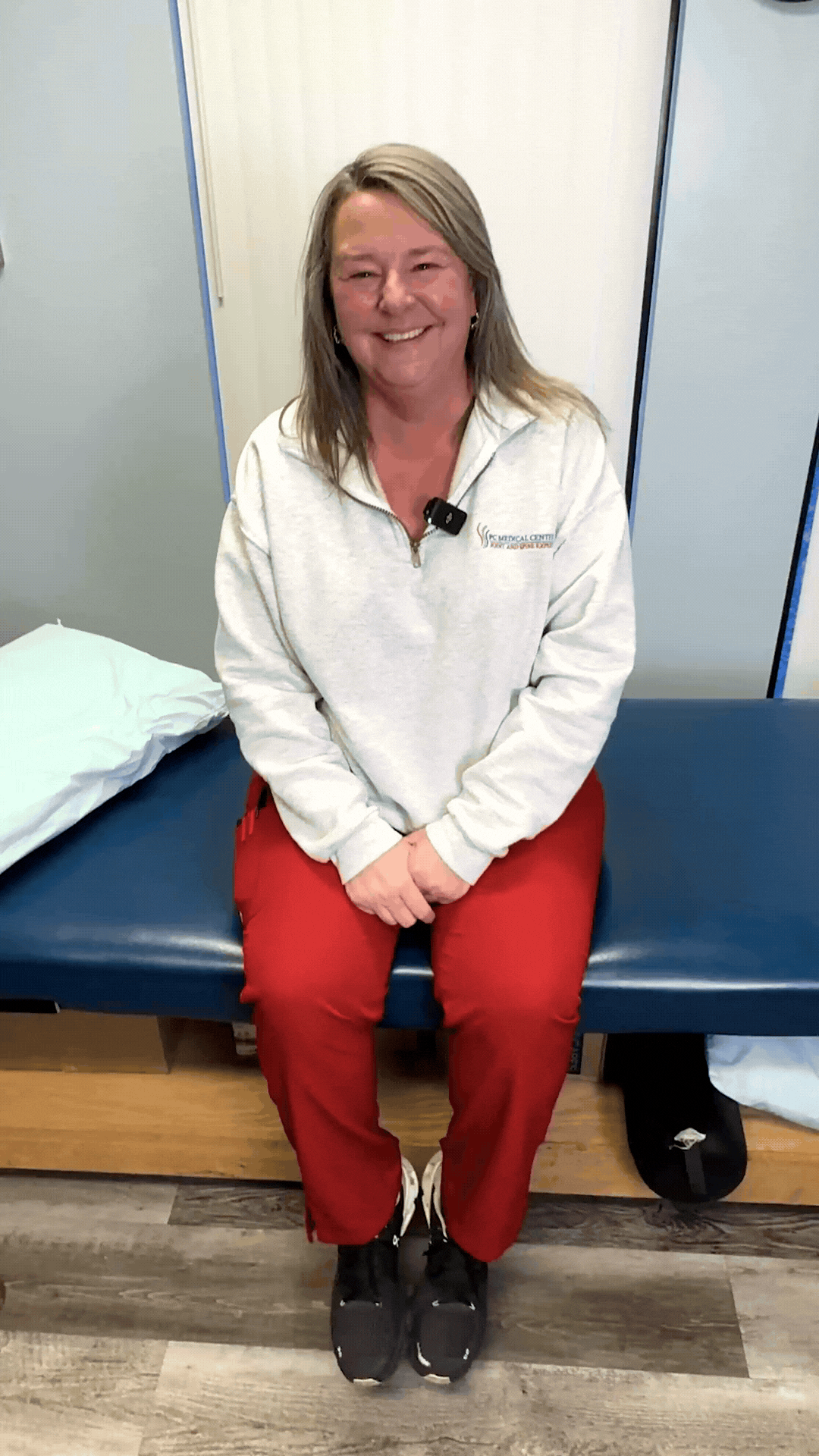 Smiling patient seated on a treatment table at PC Medical Centers, sharing her testimonial