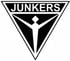 Schwarzes, auf der Spitze stehendes Dreieck mit weißer Schrift "JUNKERS" oben und einer stilisierten menschlichen Figur in der Mitte.