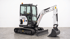 Kompakter Bobcat E17 Minibagger mit Kettenantrieb, Schneideblatt und Greifschaufel, beschriftet mit "SCHRASS METTRAX".