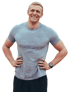 Lächelnder Mann mit grauem Sportshirt und Smartwatch, die Hände in die Hüften gestemmt.