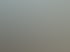 Ein Mann baut eine braune Sichtschutzwand auf einer Schotterfläche neben Mutterboden.