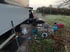 LKW-Pannenhilfe am Straßenrand mit Werkzeug, Ersatzreifen und einem mobilen Stromgenerator auf einer Wiese.