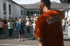 Ein Coach in orangefarbenem T-Shirt leitet eine Gruppe von Kindern bei sportlichen Übungen auf einem Schulhof an.