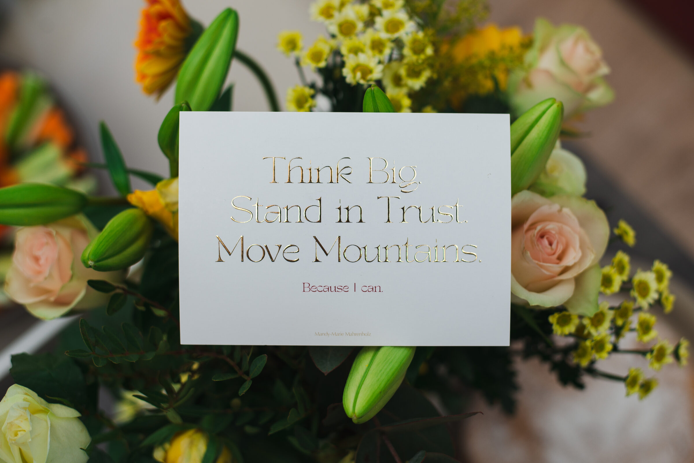 Goldveredelte Karte mit dem Leitsatz Think Big. Stand in Trust. Move Mountains. in einem Blumenstrauß beim Event The Art of Presence