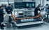 Engineers examine a Zero Drivetrain Engagement electric vehicle chassis with a large battery and two electric motors.