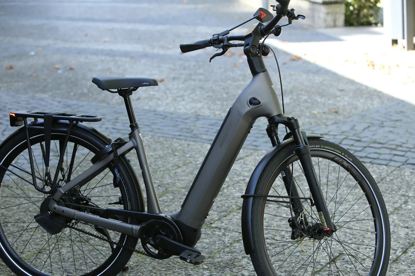 Graues Tiefeinsteiger-eBike auf dem Kopfsteinpflaster vor dem Laden