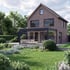 Zweifamilienhaus aus Backstein mit Wintergarten und Garten mit Rasen, Sträuchern und Blumen.