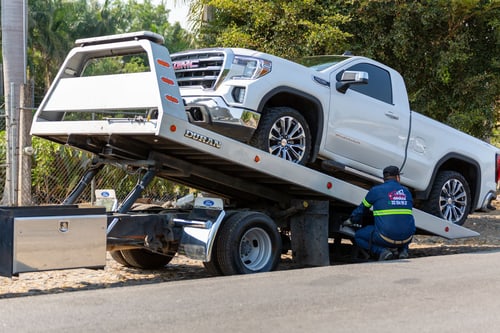 Flatbed tow truck loading a vehicle after a car breaks down on I-15 in Sandy, Utah.