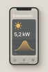 Ein Smartphone zeigt eine Solarstrom-App mit 5,2 kW Leistung und einer Kurve der Energieproduktion.
