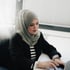 Eine Frau mit grauem Hijab und gestreiftem Oberteil tippt an einem weißen Schreibtisch auf einer Tastatur.