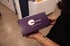 Hands holding a dark purple "mescreen Patient Sample Collection Kit" box