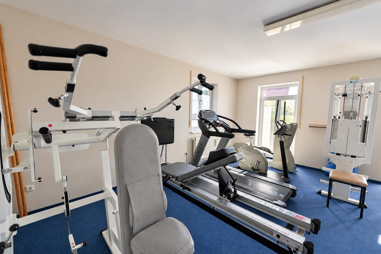 Übungsraum mit Trainingsbank, Laufband und Sprossenwand am Fenster