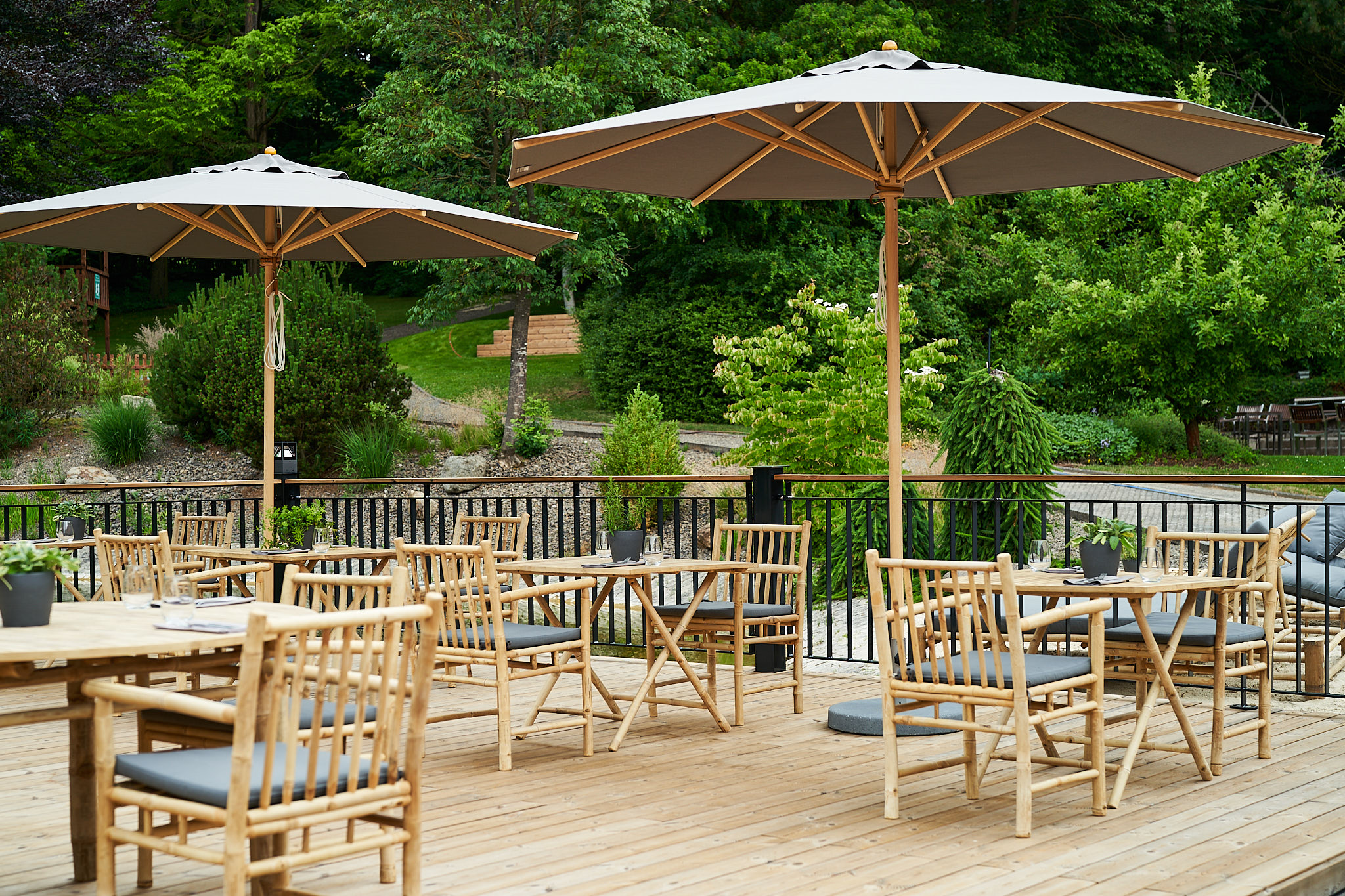 Holzterrasse mit Tischen und Sonnenschirmen im Außenbereich