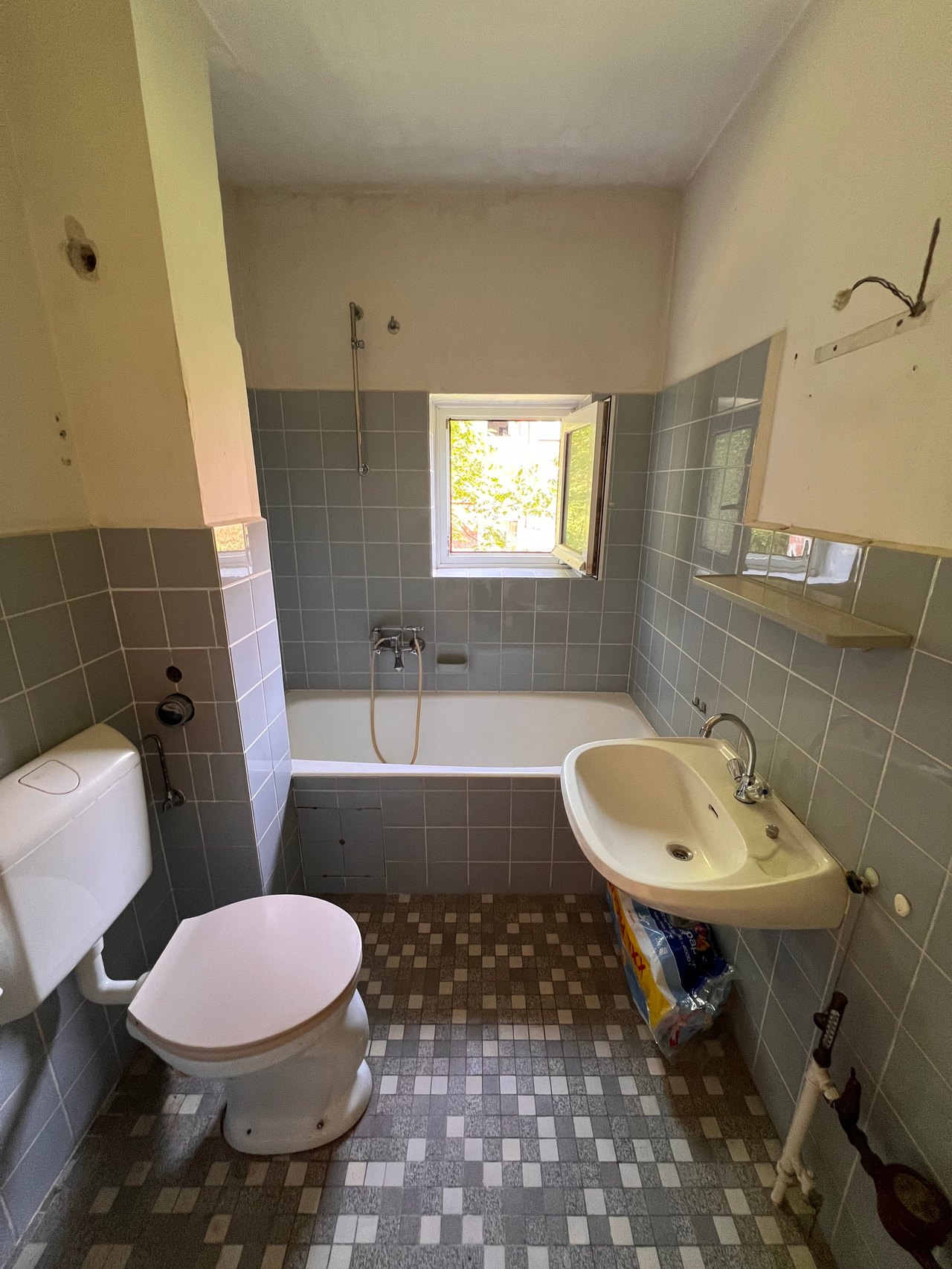Altes Bad mit Mosaikfliesen und Badewanne vor der Sanierung
