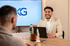 Zwei Männer unterhalten sich an einem Tisch, im Hintergrund ein Bildschirm mit dem "KKG Consulting" Logo.