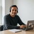 Teilnehmer mit Headset nimmt am Laptop am Live-Unterricht teil und macht sich Notizen