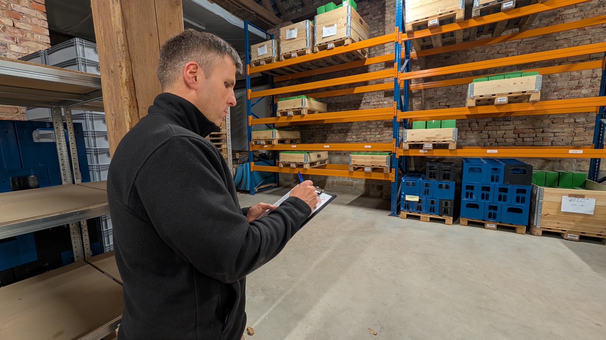Dominic Sonntag notiert im Lager der SonntagsSAFT GmbH Bestände auf einem Klemmbrett