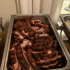 Geschnittenes gebratenes Schweinefleisch mit knuspriger Schwarte in einem silbernen Buffetbehälter.