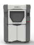 Ein grauer und weißer Stratasys Fortus 450mc 3D-Drucker mit einem Fenster und einem roten Not-Aus-Knopf.