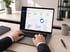Hände tippen auf Laptop mit Analytics-Dashboard, das Einnahmen, Besuche und globale Daten anzeigt.