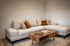 Beiges Ecksofa mit braunen Kissen und Holztisch auf hellem Teppich in modernem Wohnzimmer.