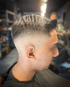 Kopf eines Mannes mit einem modernen Fade-Haarschnitt, Seite und Hinterkopf kurz, oben länger und nach hinten gestylt.