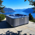 Grauer Whirlpool mit Blick auf einen großen blauen See und Berge unter klarem Himmel.