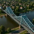 Die Blaue Brücke mit Fachwerk über einen Fluss, umgeben von Bäumen und Häusern unter blauem Himmel.
