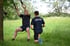 Ein Mann trainiert im Freien an Turnringen, während sein Trainer daneben kniet.
