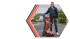 Ein lächelnder Mann steht neben einem orange-schwarzen Diagnosegerät auf einem Parkplatz.