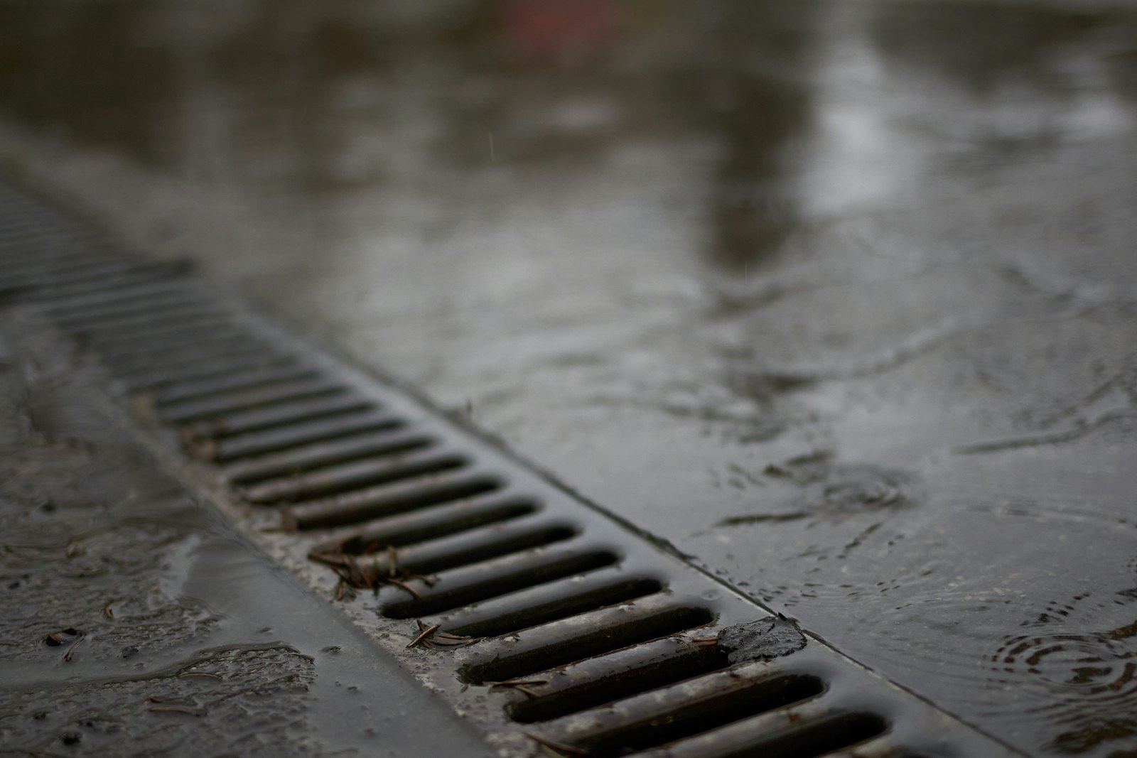 Metal roof drain on a wet surface, illustrating ponding water on a flat roof in Carrollton, TX