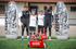 Vier Jungen, zwei Erwachsene und zwei Kinder, stehen mit einem roten Roboter und zwei Keeper Sport aufblasbaren Zielen auf einem Fußballfeld.