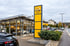 Außenansicht des Opel Autohauses Wetterauer mit gelber Pylon-Werbesäule und Neuwagen im Glas-Showroom.