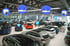 Autohaus mit Überwachungskameras, WLAN-Routern und Wi-Fi-Symbolen über mehreren ausgestellten Autos.