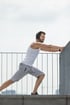 man wearing headphones and gray shorts stretches his leg against a railing while undergoing low testosterone treatment