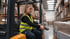 Frau im Gabelstapler scannt Paket in einem Lagerhaus.