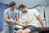 A physical therapist helps a man with arm exercises for sports recovery.