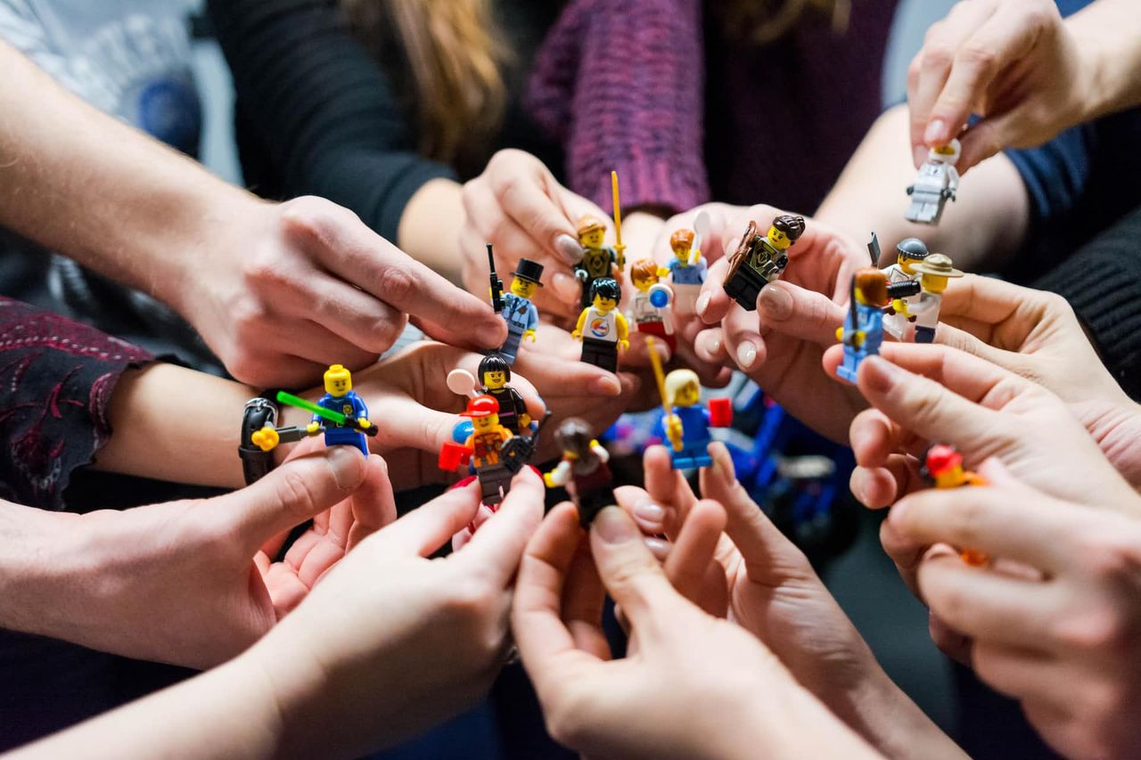 Mehrere Hände halten kleine Spielfiguren als Symbol für Zusammenarbeit
