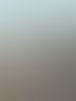 Altes, verfallenes Gebäude mit abgeblättertem Putz, sichtbaren Ziegeln und leeren Fenstern unter einem hellblauen Himmel.