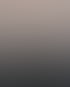 Silhouette einer sitzenden Person auf einem Felsen vor einem bewölkten Abendhimmel bei Sonnenuntergang.