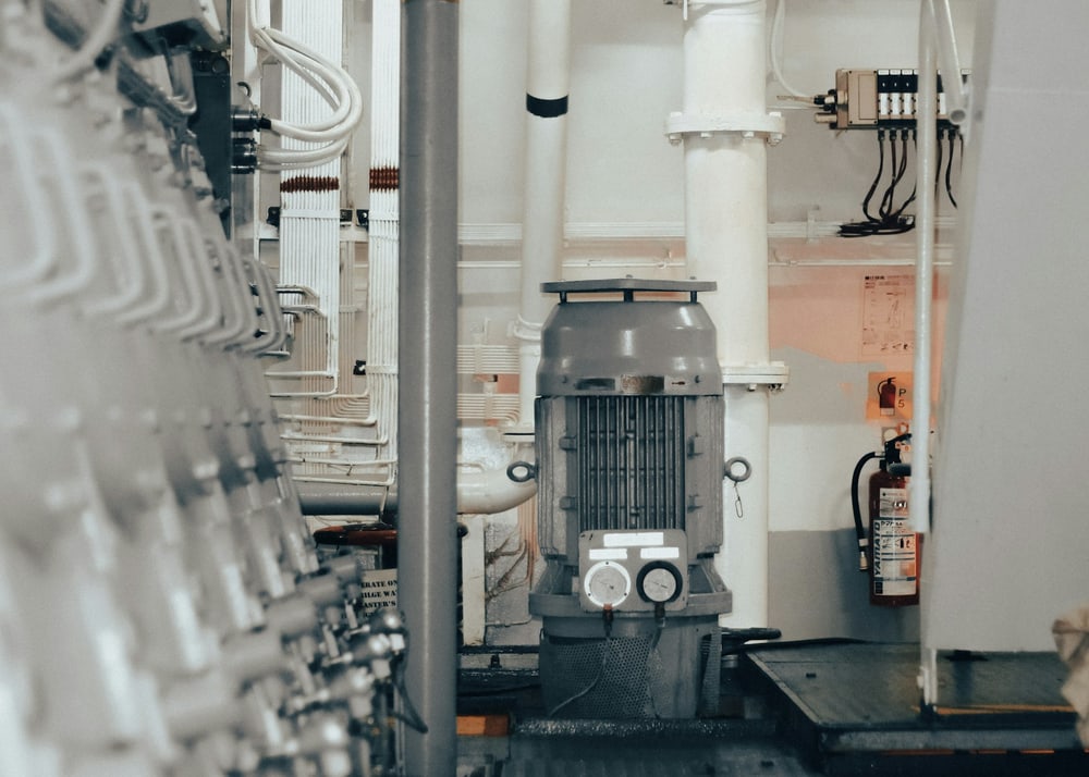 Elektromotor einer Pumpe in einem technischen Anlagenraum mit Rohrleitungen