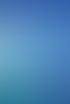 Flugzeugflügel über Küstenlinie und Meer mit glitzernden Wellen und blauem Himmel.
