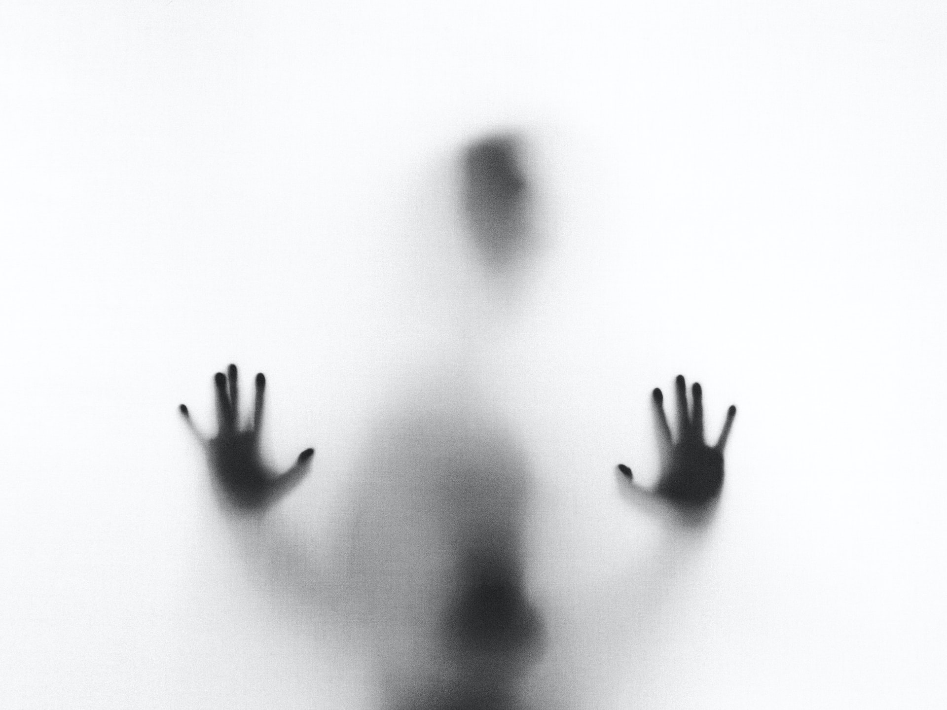 Person hinter beschlagenem Glas, Gesicht und Hand nur schemenhaft zu erkennen
