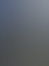 Eine beige Steinfassade eines Gebäudes mit vielen Fenstern und einer verzierten Dachkante unter einem wolkigen Himmel.