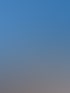 Ein orangefarbener Kirchturm mit grünem Kuppeldach und einer Turmspitze unter klarem blauem Himmel.