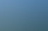 Segelboote auf einem blauen See vor bewaldeten Hügeln unter leicht bewölktem Himmel.
