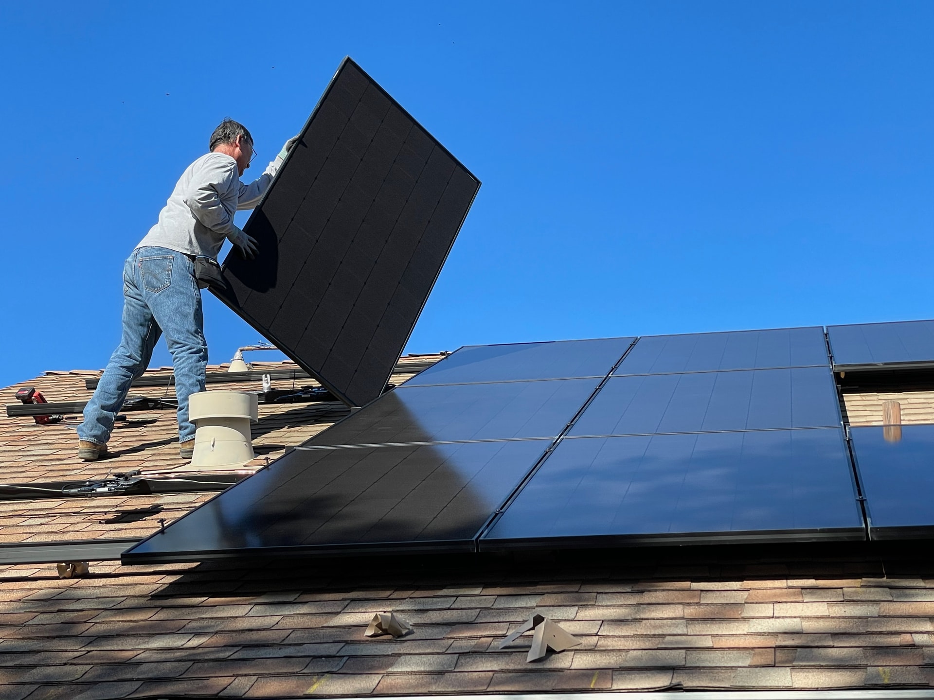 Montagetrupp befestigt Solarmodule auf einer Aluminium-Unterkonstruktion auf einem Ziegeldach